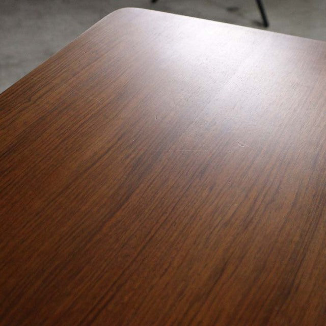 Mid-century vintage British teak dining table with smooth wood grain and rounded rectangular edges, supported by slender.