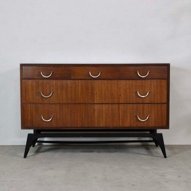 Mid-century vintage teak chest by Meredew with three drawers, sleek British design, elegant wood grain, and black tapered.