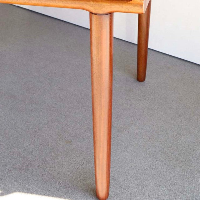 Vintage British mid-century teak dining table corner with smooth wood grain and tapered round legs.