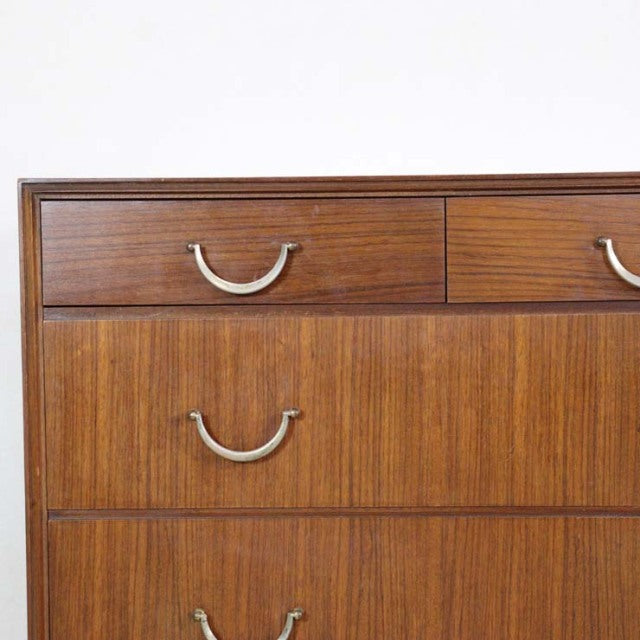 Mid-century British vintage teak chest with rich wood grain, curved silver handles, and minimalist design.