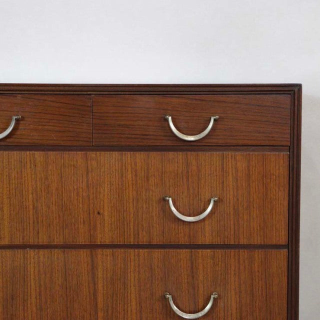 Vintage mid-century teak chest with smooth wood grain, curved metal handles, and clean British design lines.