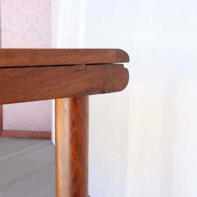 Vintage British mid-century teak dining table with rounded edges and sturdy cylindrical legs, showcasing rich wood grain and .