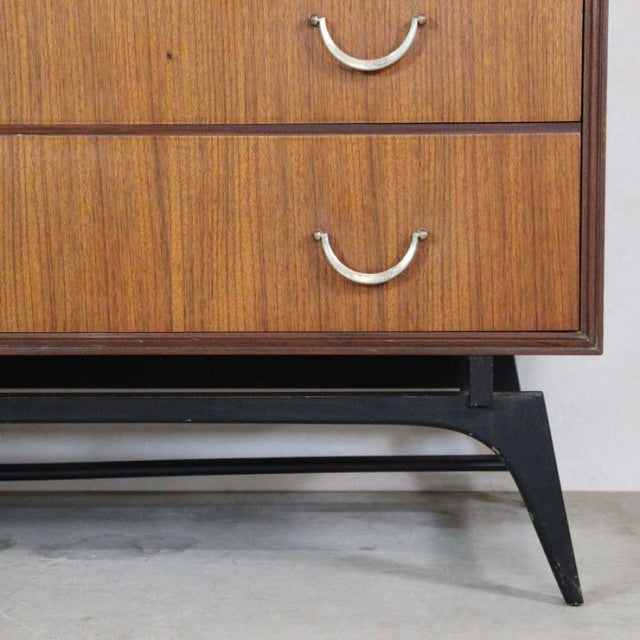 Vintage teak mid-century chest drawer corner with British Meredew label, sleek black tapered legs, and subtle wood grain.