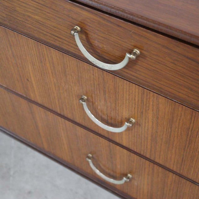 Vintage teak chest of drawers by Meredew with brass curved handles and visible mid-century British wood grain.
