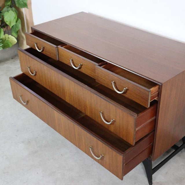 Vintage teak mid-century chest by Meredew with rich wood grain, brass handles, and sleek black legs.