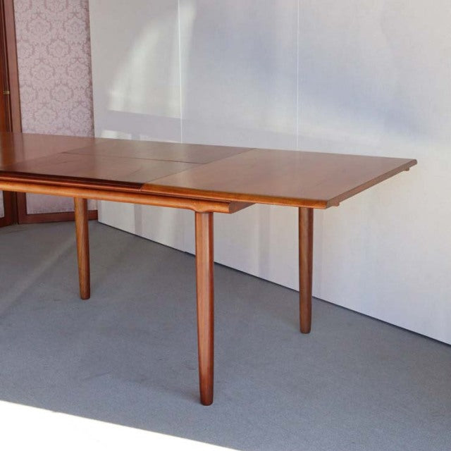 Mid-century British teak dining table by WhiteANDnewton with rectangular top, tapered legs, and smooth wood grain finish.