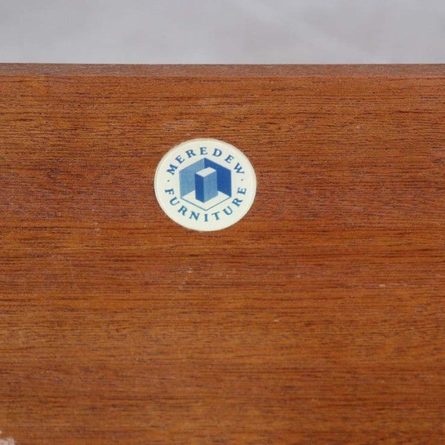 Close-up of vintage Meredew teak wood surface with subtle grain and round blue-and-white British furniture logo from.