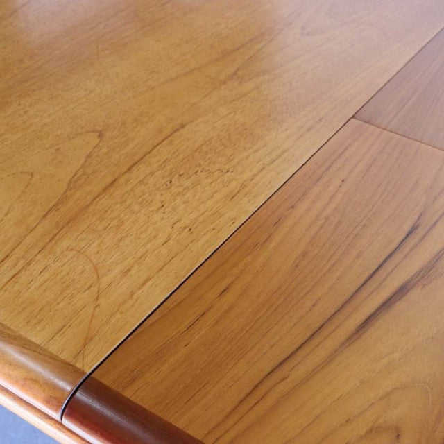 Vintage British mid-century teak dining table with smooth wood grain and rectangular top, sleek angled legs.