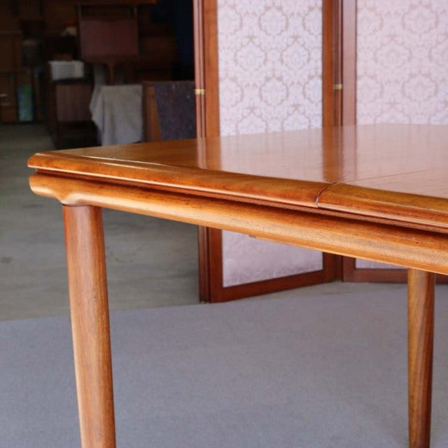 Vintage British mid-century teak dining table with smooth rounded edges and slender tapered legs.