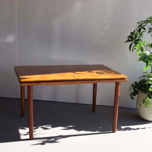 Vintage British mid-century teak dining table with rectangular top and tapered legs, smooth wood grain finish.