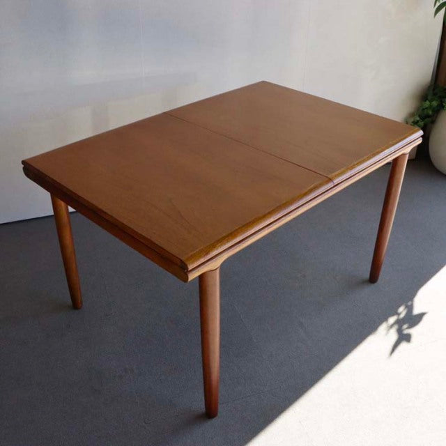 Vintage British mid-century teak dining table by WhiteANDnewton, rectangular with smooth wood grain and tapered legs.
