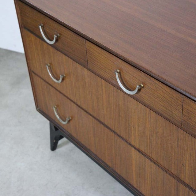 Mid-century British vintage teak chest with rich wood grain, curved silver handles, and black angled legs from Meredew.