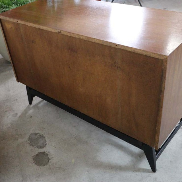 Mid-century British vintage teak chest with sleek wood grain, minimalist form, and sturdy dark tapered legs, crafted by.
