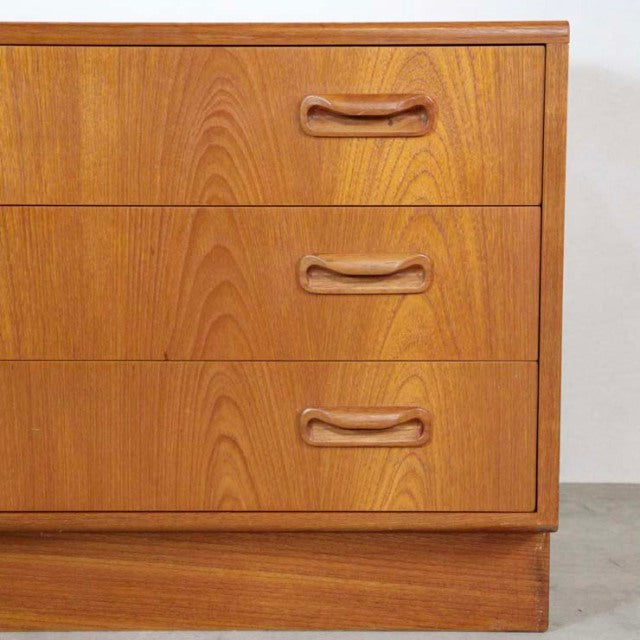 Vintage G-plan mid-century teak chest of drawers with three smooth wood grain drawers and curved recessed handles on a solid .
