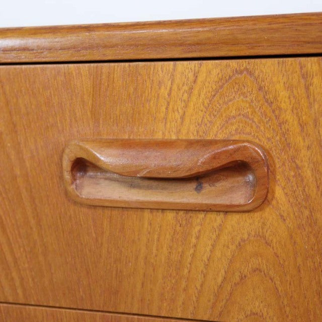 Close-up of vintage teak drawer handle on British mid-century G-Plan Fresco chest showing warm wood grain and smooth rounded .