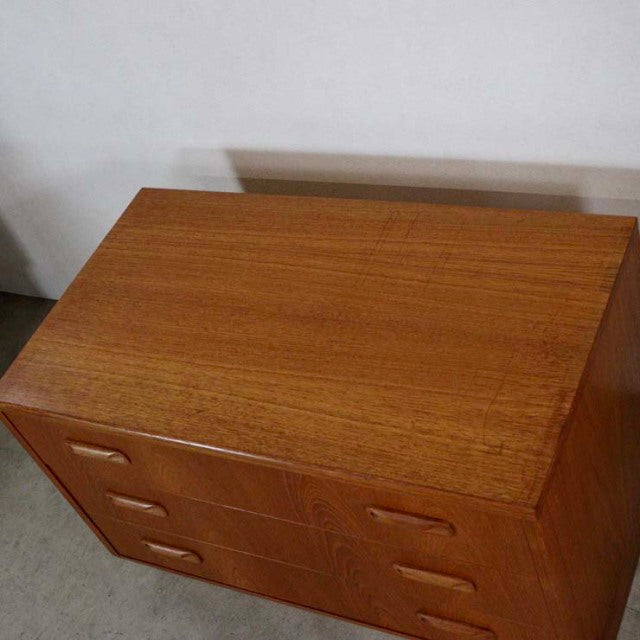 Vintage British G-Plan mid-century teak three-drawer chest with smooth wood grain and tapered legs.