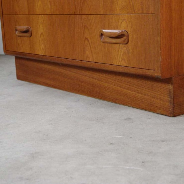 Mid-century British G-plan vintage teak chest with three drawers, sleek wood grain, and integrated handles on a solid base.