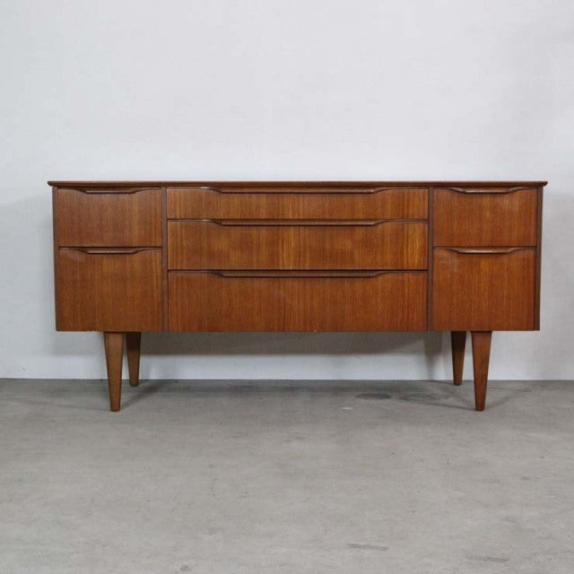 Mid-century vintage British teak sideboard with rich wood grain, tapered legs, and streamlined drawers.