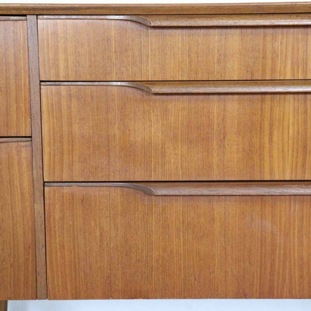 Mid-century British vintage teak sideboard drawers showing smooth wood grain and integrated curved handles.