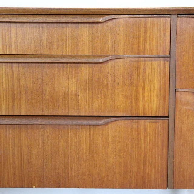 Vintage British mid-century teak sideboard drawer front with rich wood grain and integrated handles.