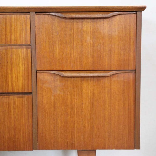 Vintage teak sideboard doors with rich wood grain and sculpted handles, mid-century British-Denmark design.