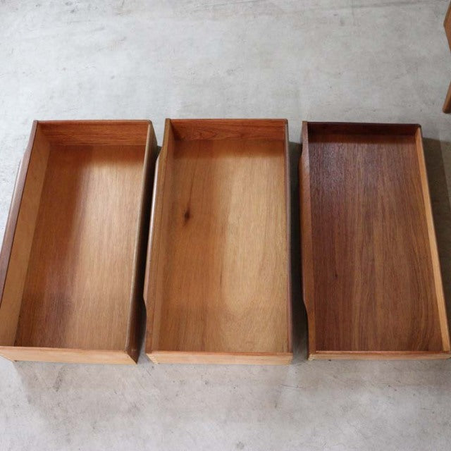 Three vintage teak drawers with rich wood grain, showcasing mid-century British and Danish design.