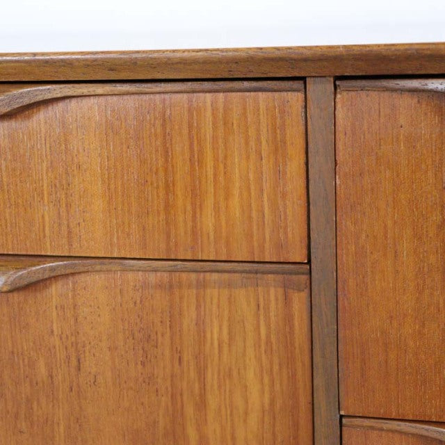 Mid-century British vintage teak sideboard with rich wood grain and curved recessed handles.