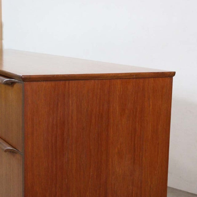 Vintage teak mid-century British sideboard with smooth wood grain and rounded fretwork handles.