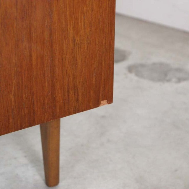Mid-century British vintage teak sideboard corner with tapered round leg and rich wood grain.