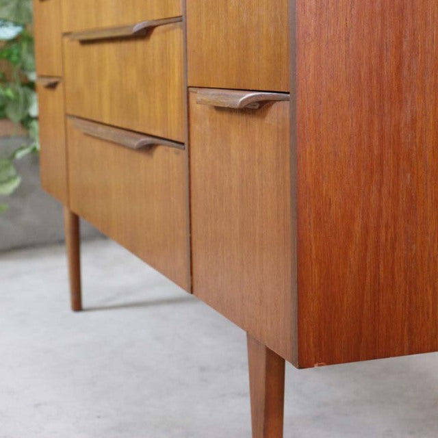 Mid-century British vintage teak sideboard with smooth wood grain, tapered legs, and integrated handles.