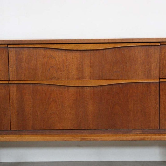 Vintage mid-century British teak sideboard by Austinsuite with smooth wood grain and curved drawer handles.