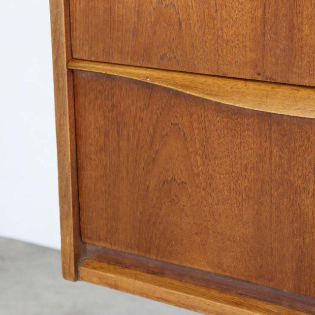 Close-up of vintage British mid-century Austinsuite teak sideboard drawer with smooth wood grain and curved handle detail.