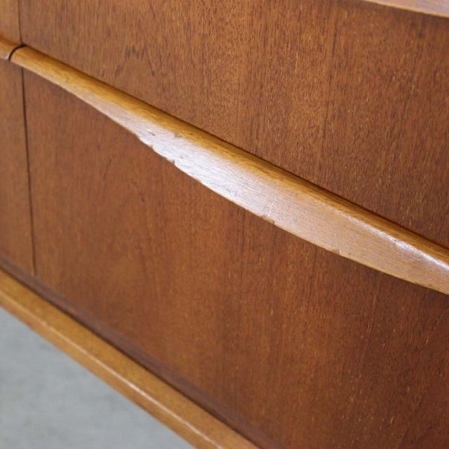 Close-up of vintage British teak sideboard door with smooth wood grain and mid-century curved handle design from.