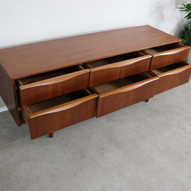 Mid-century British vintage teak sideboard by Austinsuite with six curved front drawers and tapered legs.