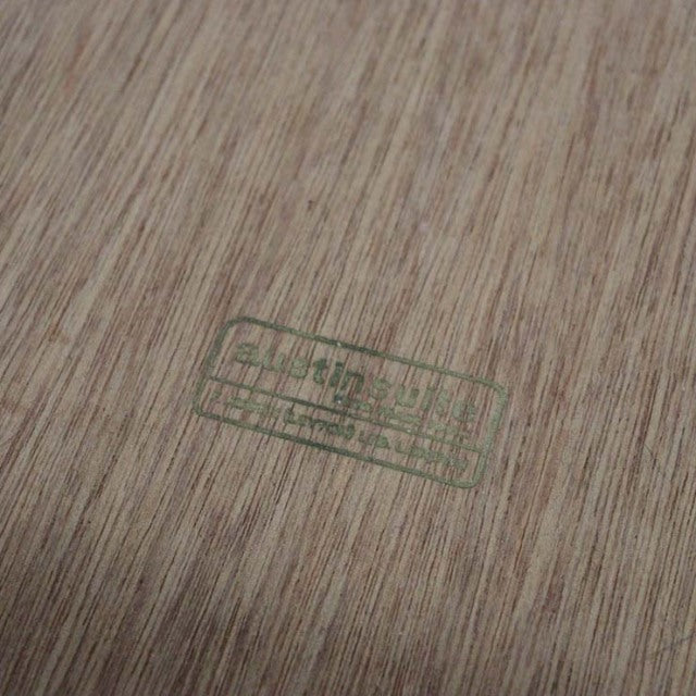 Close-up of vintage teak wood grain with British mid-century Austinsuite stamp in green ink from Denmark sideboard.
