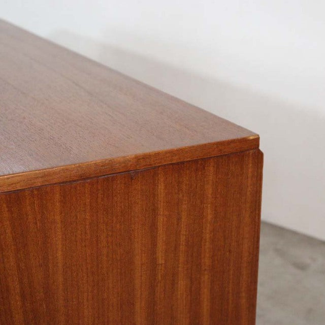 Close-up of vintage mid-century British teak sideboard corner, showcasing smooth wood grain and clean lines.