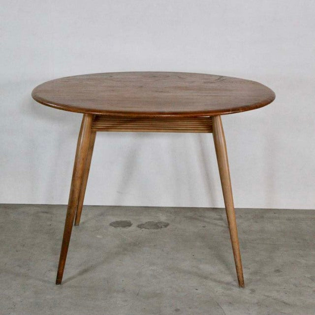 Vintage mid-century British Ercol dining table in warm teak with smooth oval top and tapered legs showcasing natural wood.