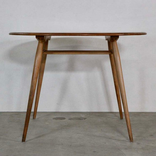 Vintage British mid-century ERCOL dining table in teak with rounded rectangular top and tapered legs connected by stretcher.