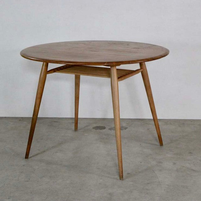 Vintage British mid-century ERCOL dining table in teak with round top and tapered legs.