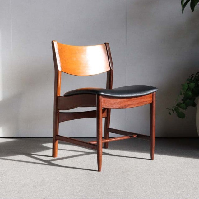 Mid-century British vintage teak dining chair with curved backrest and black cushioned seat, showcasing rich wood grain and.