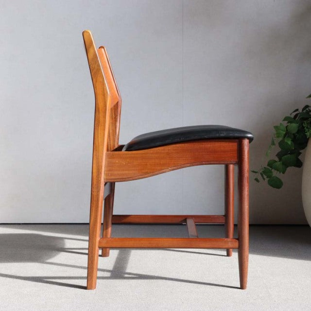 Mid-century British vintage dining chair in teak wood with smooth grain, black cushioned seat, and tapered legs from Denmark.