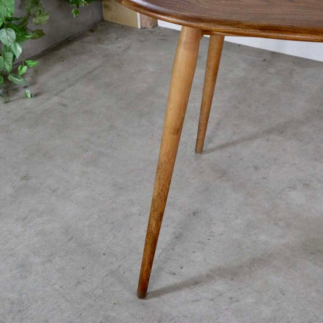 Mid-century vintage ERCOL teak dining table leg with tapered profile and warm wood grain finish on concrete floor.