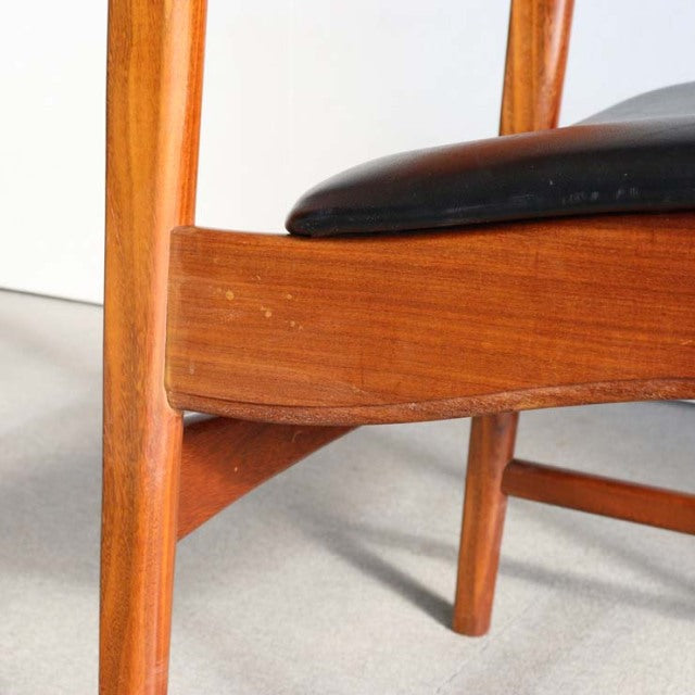 Mid-century British teak dining chair with sleek wood grain and black leather cushion, Danish-inspired design.