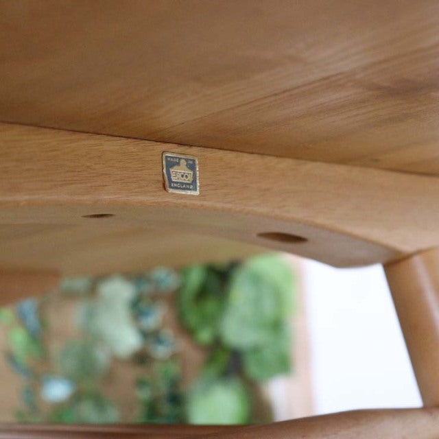 Underside of vintage British ERCOL teak dining table showing smooth curved edge, wood grain, and turned leg joint detail.