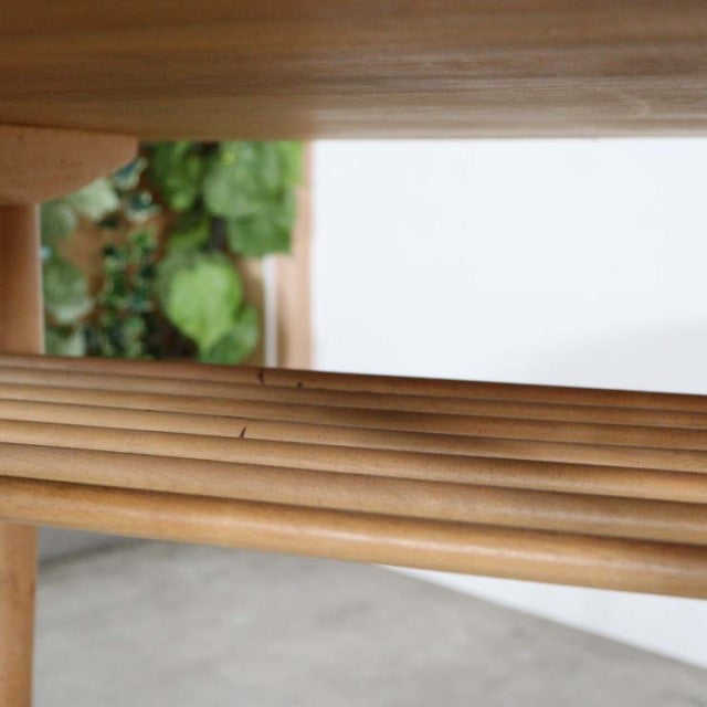 Close-up of vintage British mid-century teak dining table highlighting smooth wood grain and slatted underframe detail with.