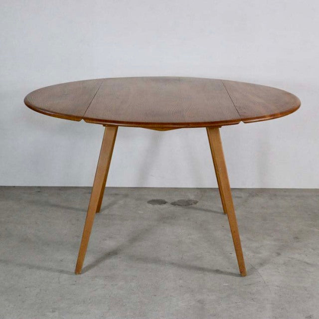 Mid-century British vintage Ercol dining table in teak with drop-leaf oval top and angled splayed legs.