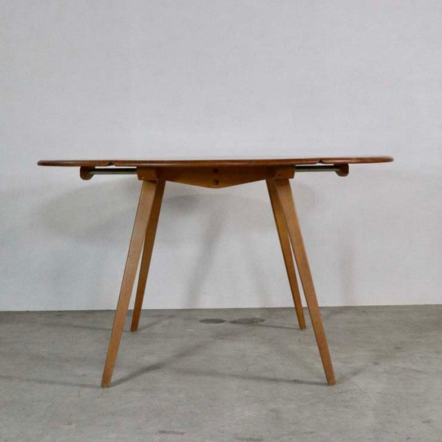 Mid-century British Ercol dining table in vintage teak with distinctive tapered legs and drop-leaf design showcasing rich.