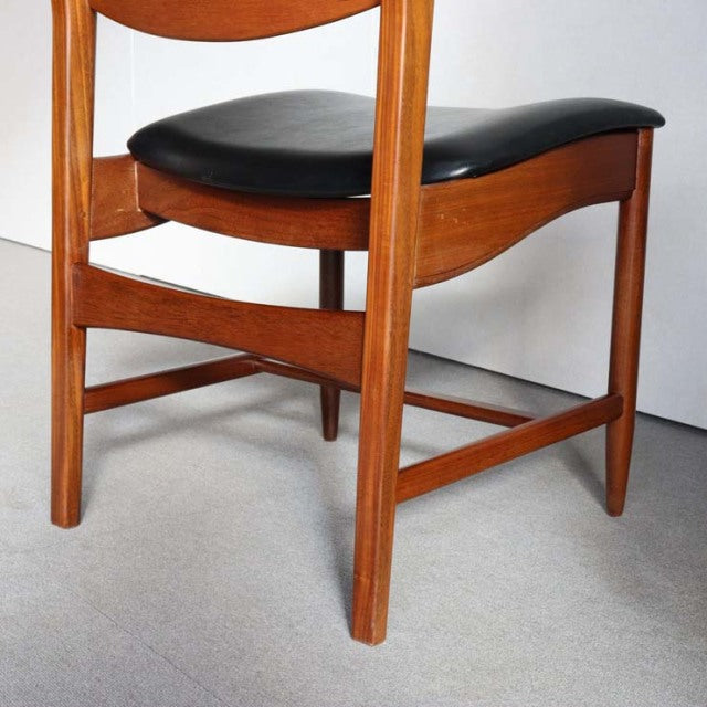 Mid-century British vintage teak dining chair with curved legs and black leather cushioned seat.
