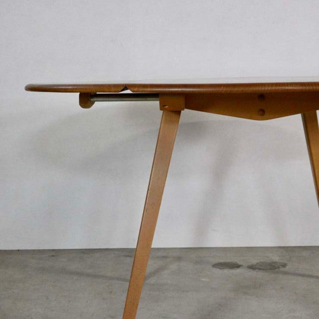 Mid-century British Ercol teak dining table with drop-leaf, angled legs, and smooth wood grain finish.