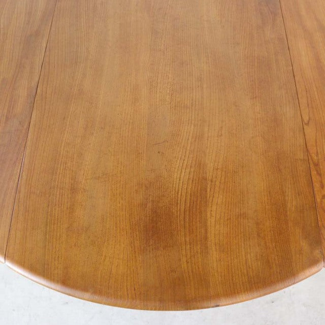 Vintage British mid-century Ercol dining table in teak with smooth wood grain and rounded drop-leaf edges.